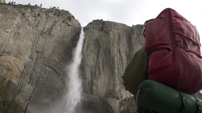 Hiker walks up to a very high waterfall