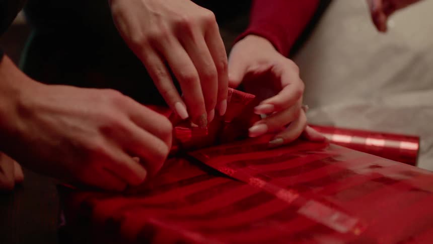 People are wrapping a christmas present together