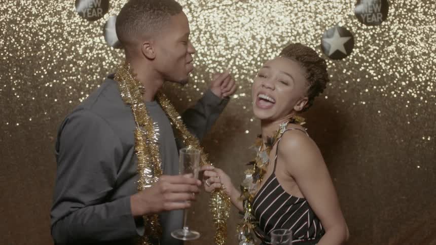 A man and woman dance while drinking champagne