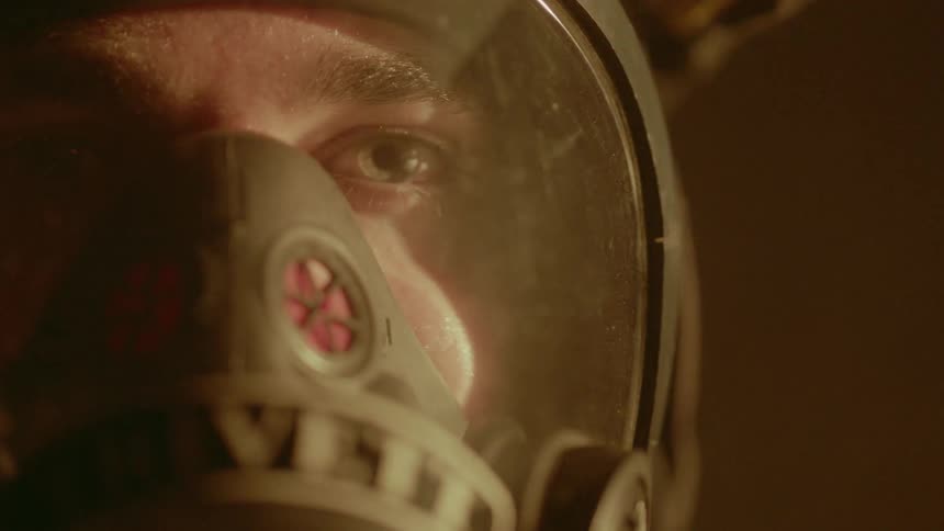 A man wearing a breather and mask is staring ahead