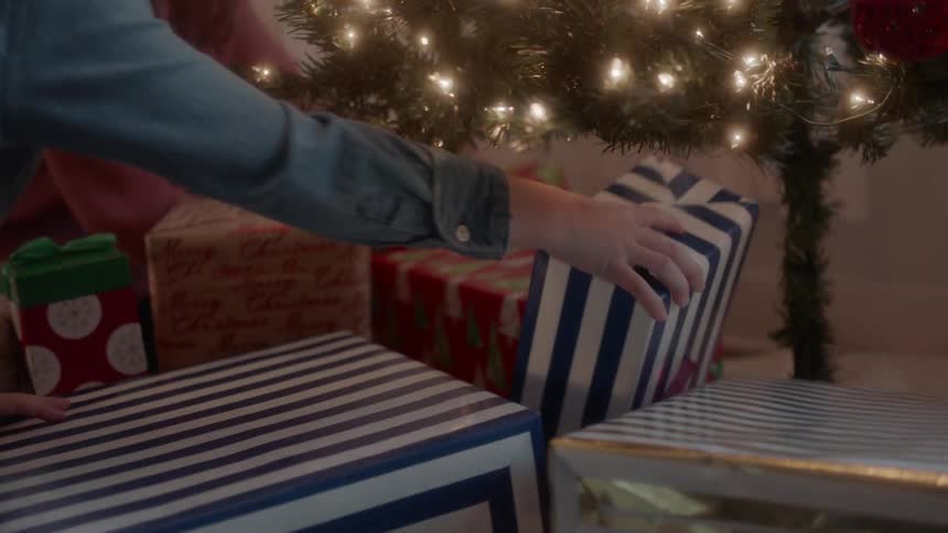 A boy shakes a wrapped gift he took out from under the tree