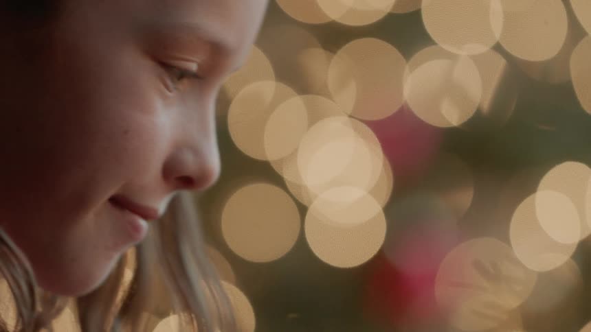 A girl smiles next to a christmas tree