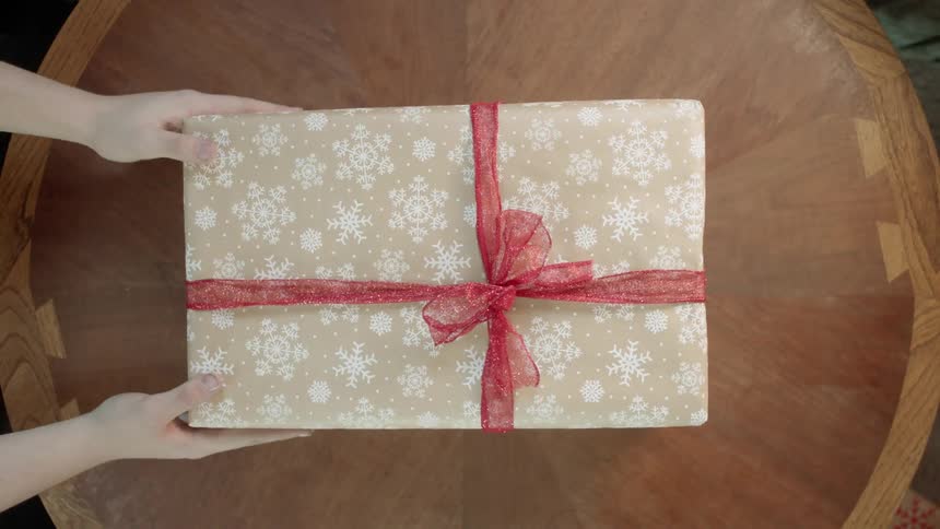 A christmas gift is removed from a table
