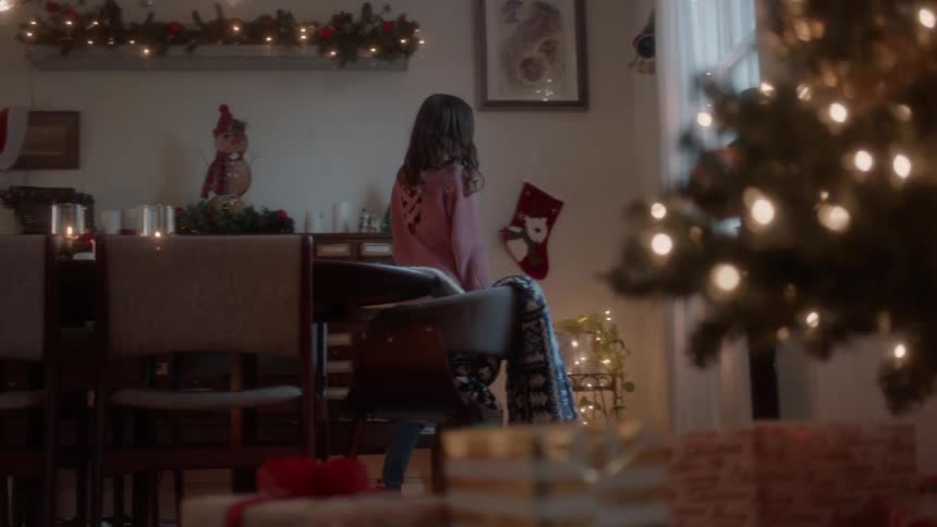A girl hangs a stocking near a christmas tree