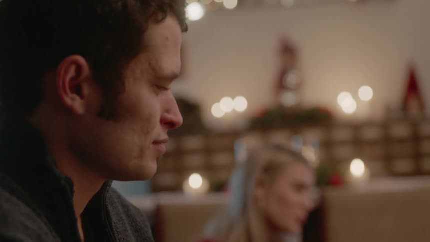 Man and woman sit in candle lit living room