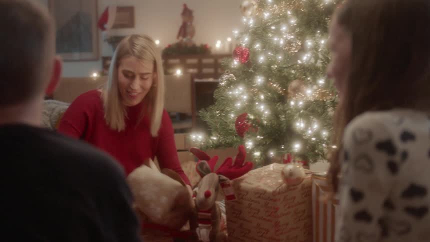 People sit around a christmas tree and open presents