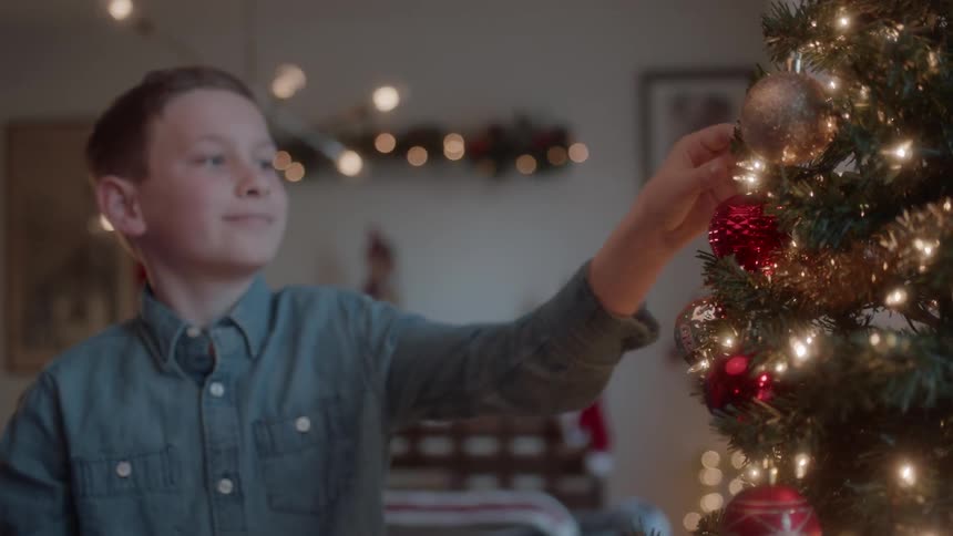 Boy places ornament on christmas tree