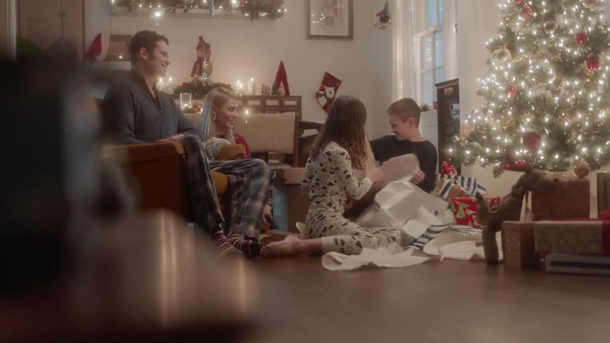 A family opens gifts next to a christmas tree