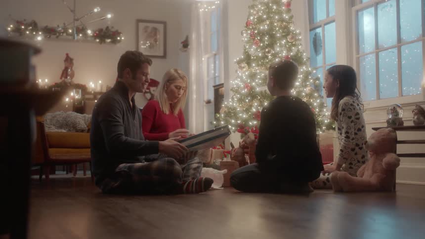 A family exchanges presents next to a christmas tree