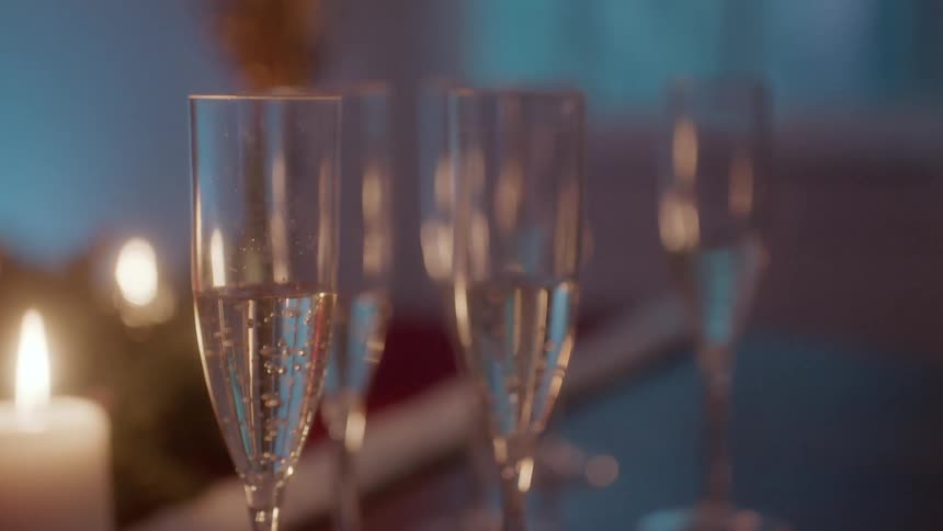 Glasses of champagne sit next to candles on a table
