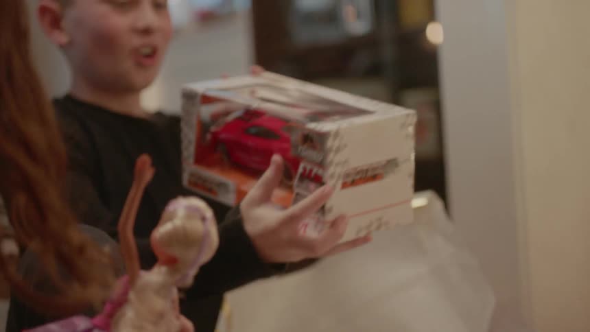 A boy and girl unwrap christmas presents