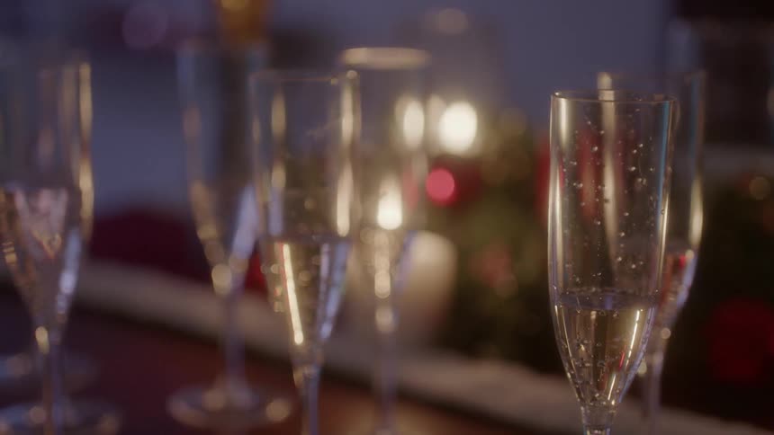 Glasses of champagne sit next to christmas decorations on a table