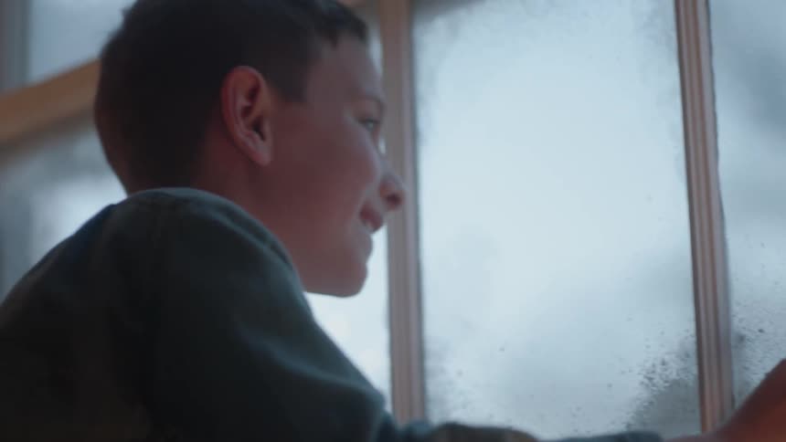 A boy smiles as he looks out the window
