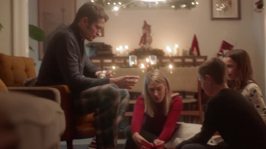 A family wraps a gift next to a christmas tree
