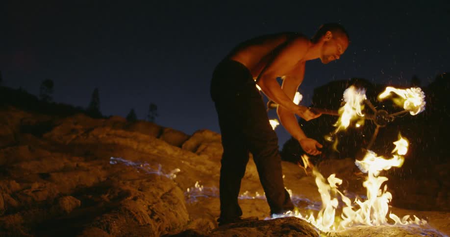 Man is fire dancing and creates ring of fire on ground