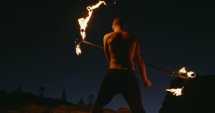 A man doing fire poi at night