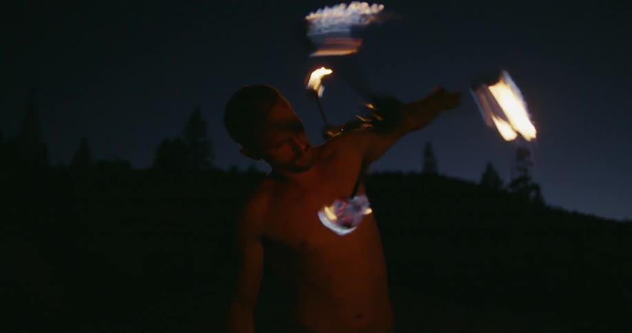 A man is twirling fire at night