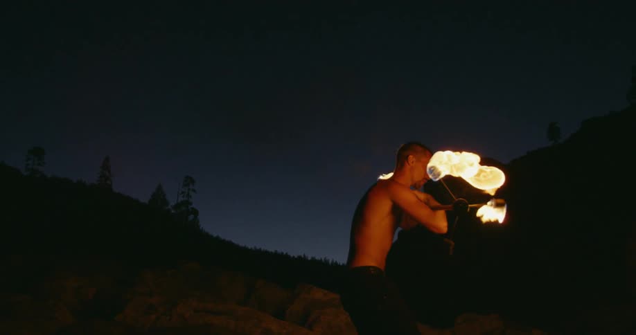 A man spins a rod with fireballs