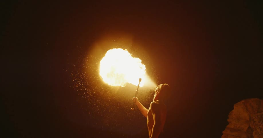 A man is breathing fire at night