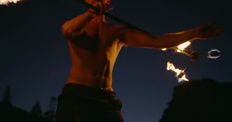 A man fire spinning at night