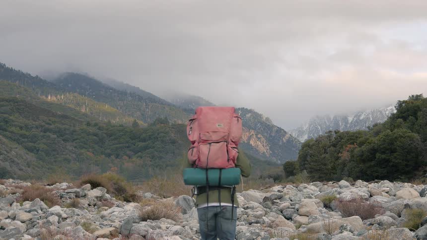 Man walking over some rocks on a cloudy day