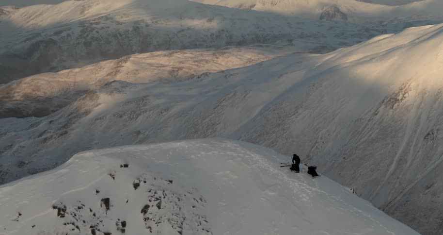 Two skiers approach a peak in a snow covered mountain range