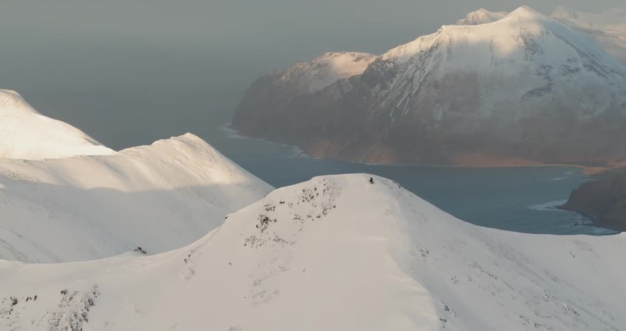 Person nearing a snowy mountain peak on a hazy day