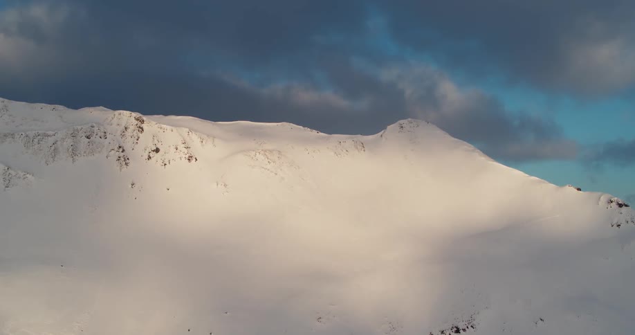 A snow covered ridge and slope on a cloudy day