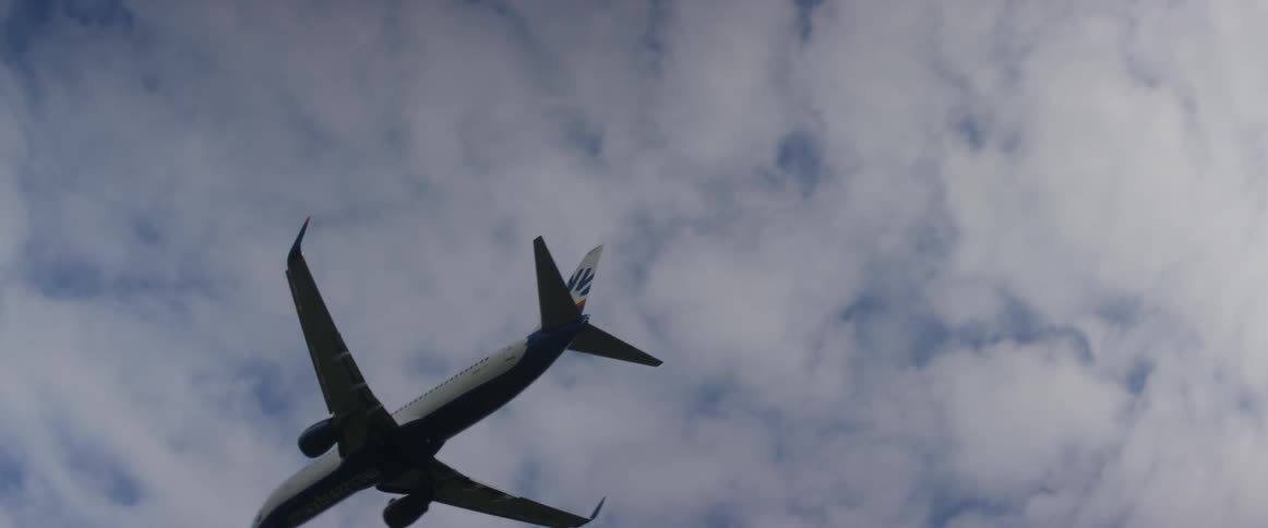An airplane flies overhead on a cloudy day