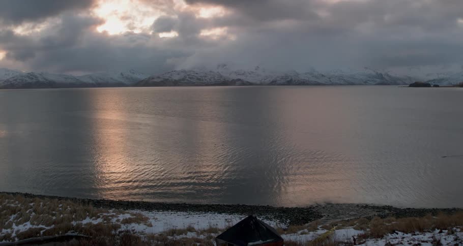 The sun sets over a mountain sea and cabin