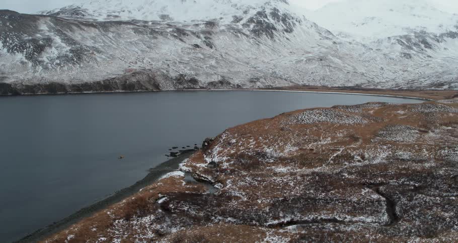 Snow covered peaks sit above the shore