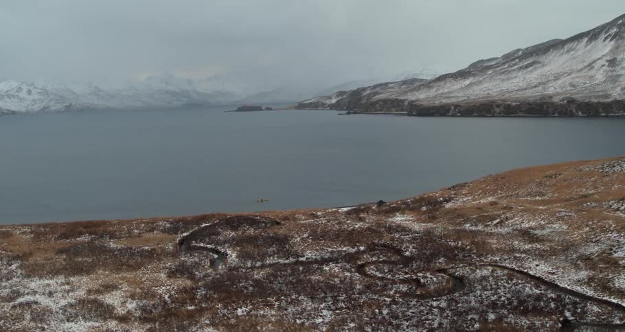 Snowy mountains surround the sea and kayaker