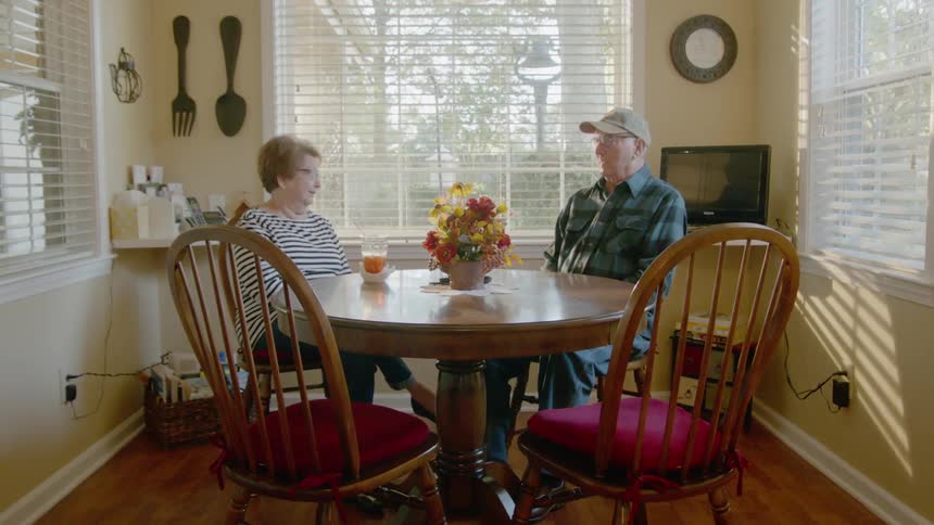 A man and woman sit at a dining room table