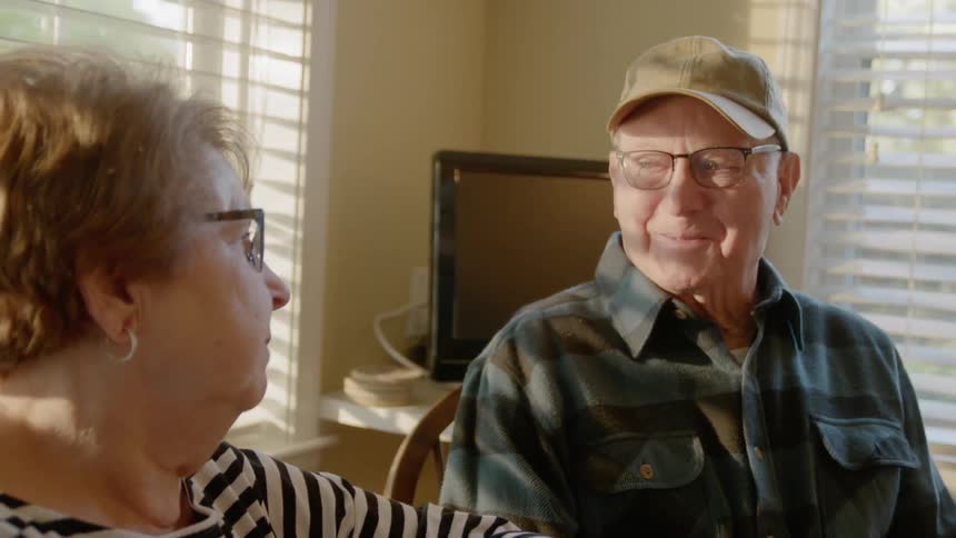 A man and woman are sitting around a table talking and laughing