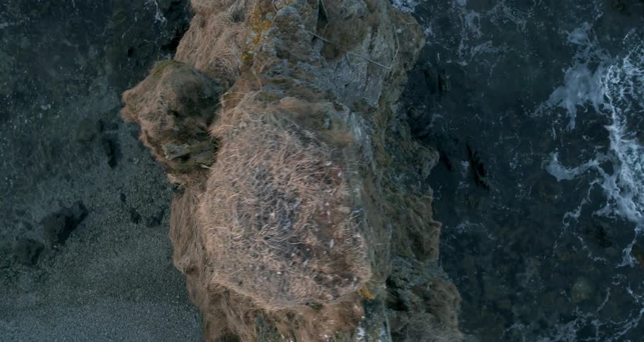 Waves lap against the rock formation near shore