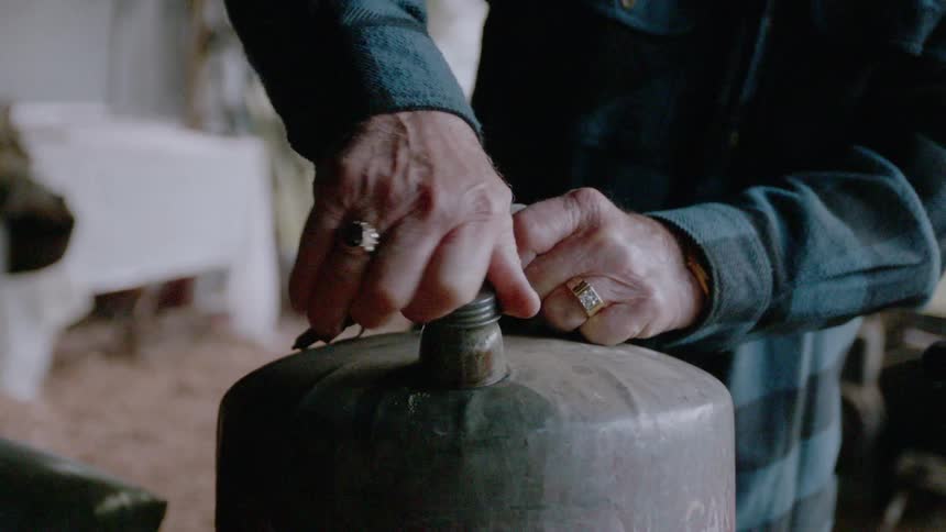 A man attaches a nozzle and lifts a container