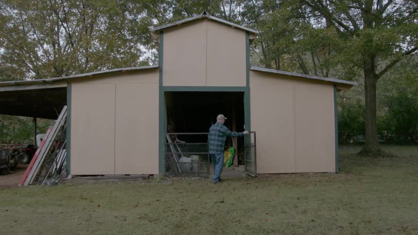 Elderly man enters a rural barn