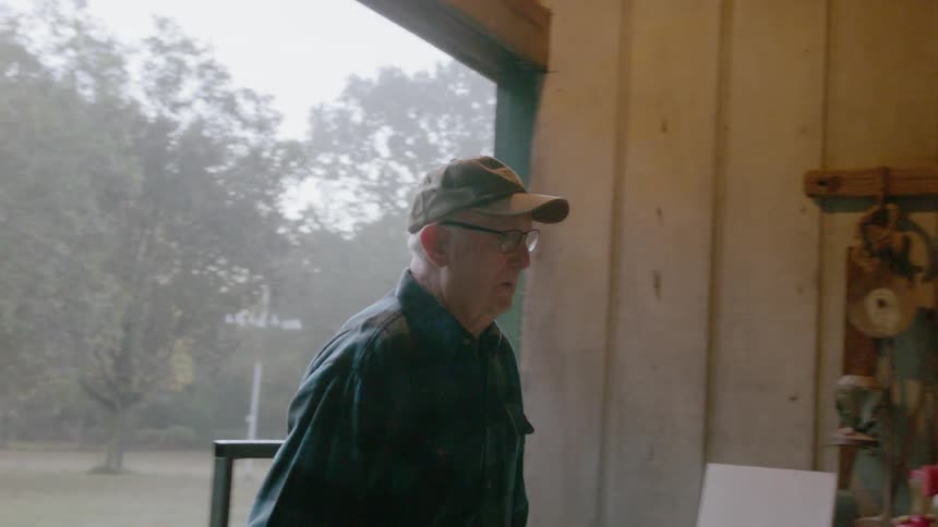 A man switches on the light and walks into a tool shed