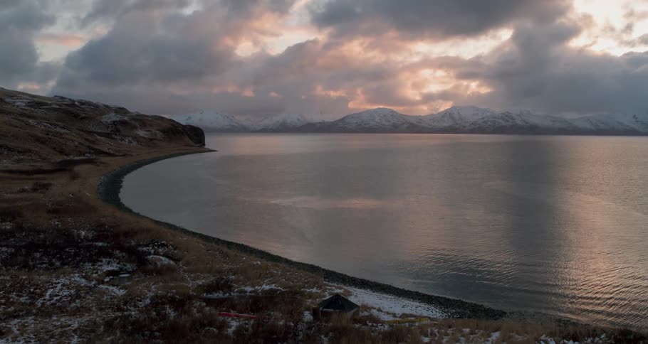 A calm sea with snow covered mountains in the distance