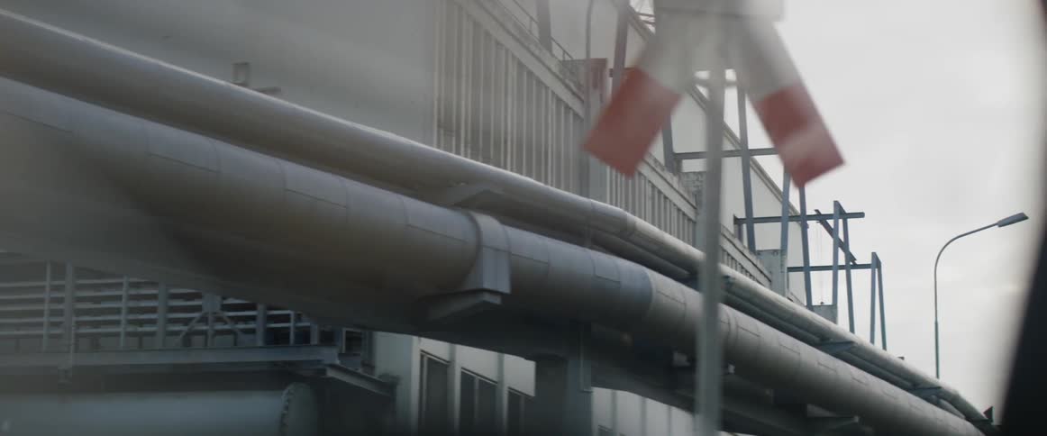A pipeline is operating outside an industrial building during the day