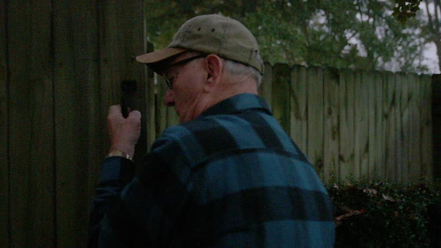A man opens a fence gate and walks through