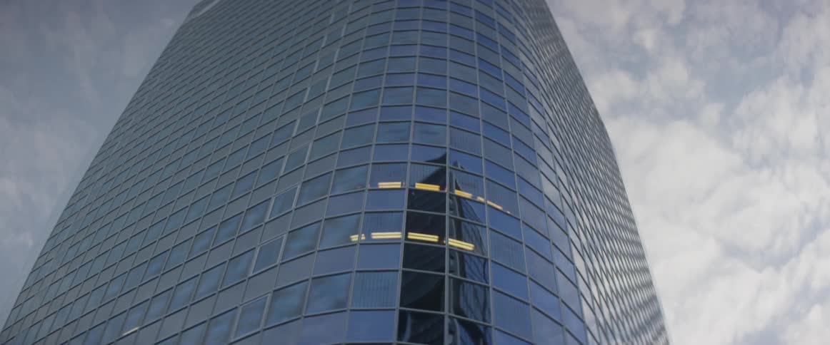A very tall building with many windows in front of a cloudy sky