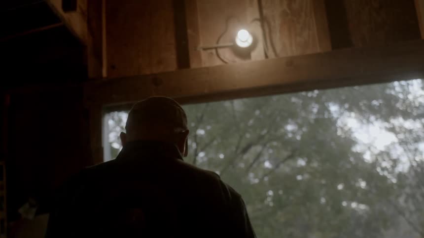 An older man is walking through a doorway in a rural setting