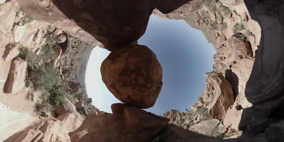 A boulder is balancing between rock formations in the desert