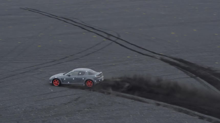 A car peels out across a black dirt plain