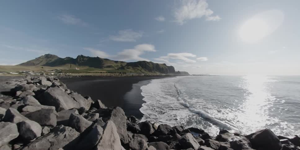 Waves are crashing onto shore on a bright sunny day
