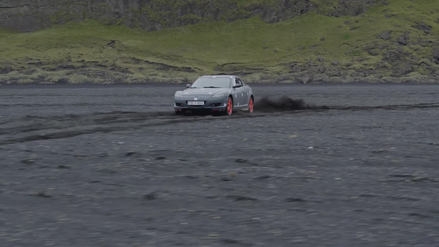 A sports car is off-roading on a beach during the day