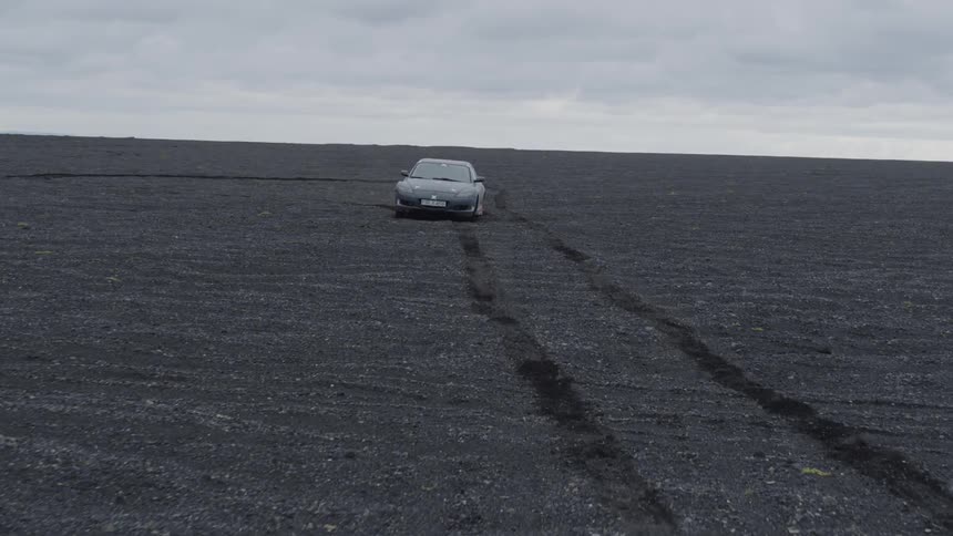 The sports car races over the dirt field