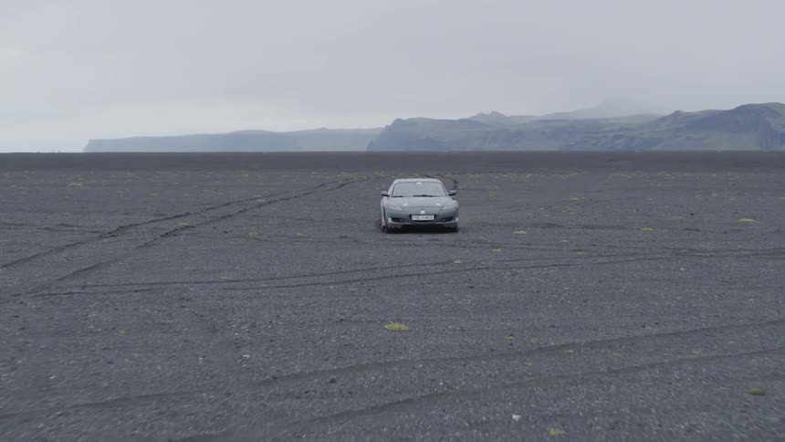 A car leaves tire tracks as it travels through dirt