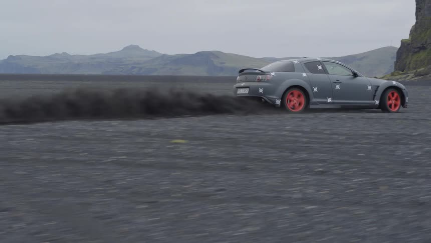 A car is driving really fast over a dirt and rock covered plain and is getting airborne over the bumps